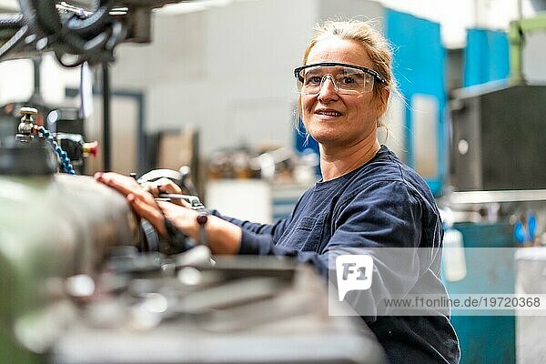 Porträt einer Fabrikarbeiterin  die im Kontrollbereich einer Metallfräsmaschine arbeitet  Industriewerk