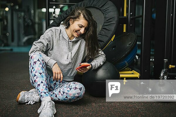 Sportliche lächelnde Frau mit Smartphone Fitnessstudio