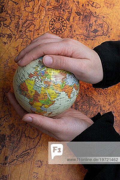 Person hält einen Globus auf einer alten Karte Hintergrund