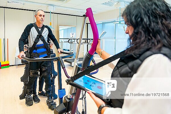 Mechanisches Exoskelett. Weibliche Physiotherapie medizinische Assistentin mit behinderten Person mit Roboterskelett angehoben. Futuristische Rehabilitation  Physiotherapie in einem modernen Krankenhaus