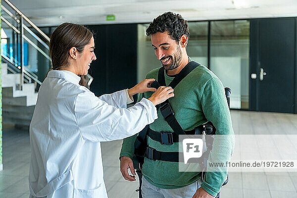 Mechanisches Exoskelett  weibliche Physiotherapeutin  die einer behinderten Person mit Roboterskelett Bänder anlegt  Physiotherapie in einem modernen Krankenhaus  futuristische Physiotherapie