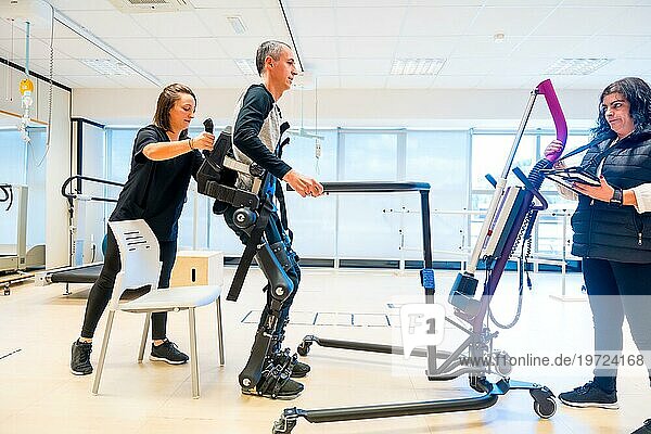 Mechanisches Exoskelett. Medizinischer Assistent in der Physiotherapie hebt eine behinderte Person mit Roboterskelett zum Aufstehen. Futuristische Rehabilitation  Physiotherapie in einem modernen Krankenhaus