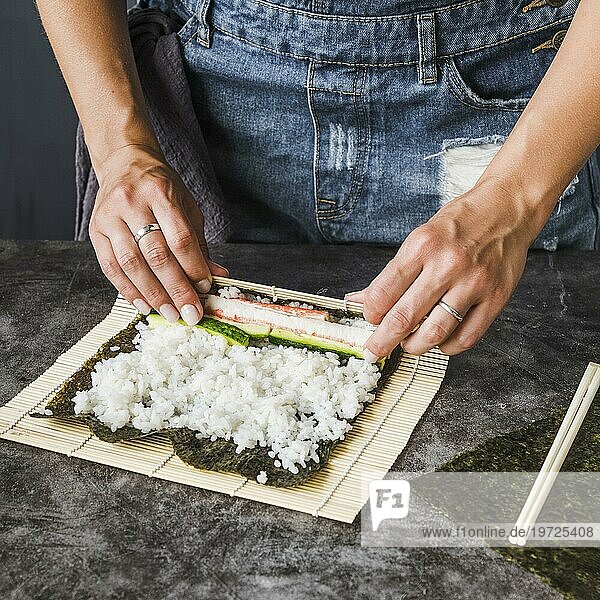 Hände wickeln Zutaten ein Sushi Matte