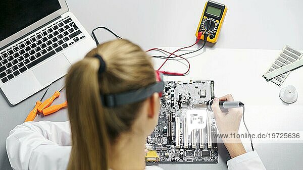 Hochgewinkelte Technikerin mit Lötkolben Elektronik Motherboard