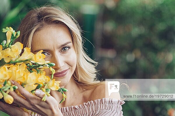 Porträt lächelnde junge Frau berührt gelbe Sia Blumen mit Sorgfalt