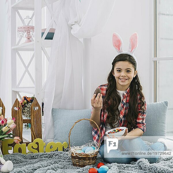 Porträt Mädchen sitzend Bett hält Ostern Schokolade Ei Schüssel Süßigkeiten suchen Kamera