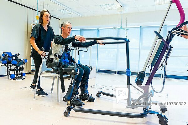 Mechanisches Exoskelett. Weibliche Physiotherapie Arzthelferin hebt behinderte Person mit Roboterskelett zum Aufstehen. Futuristische Rehabilitation  Physiotherapie in einem modernen Krankenhaus