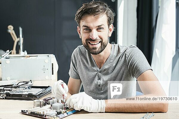 Porträt glücklicher Mann bei der Reparatur einer Computerplatine