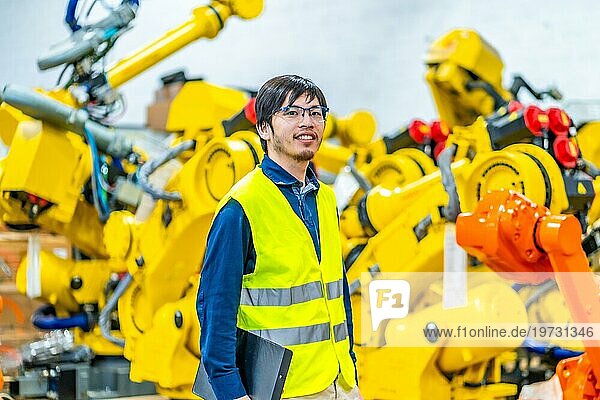 Junger japanischer Ingenieur  der ein automatisiertes Fließband in einer Fabrik leitet