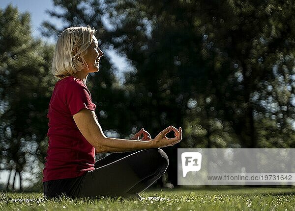 Seitenansicht ältere Frau Lotussitz im Freien während Yoga