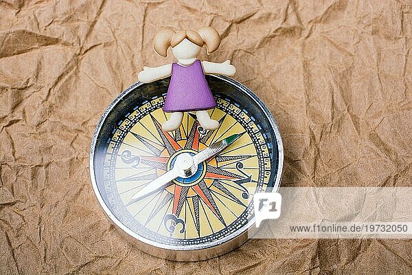 Miniatur Mädchen auf einem Kompass als Bildungs und Geschäftskonzept