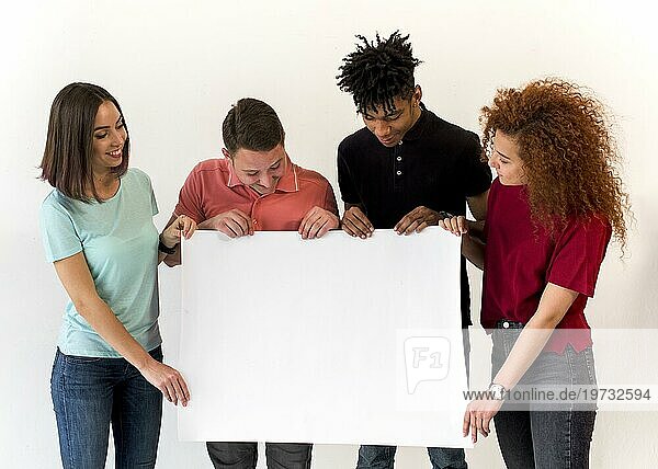 Gruppe lächelnder multiethnischer Freunde  die ein leeres weißes Plakat halten  das auf weißem Hintergrund steht