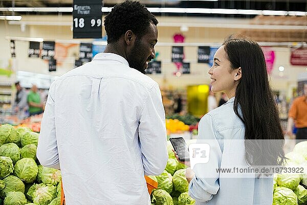 Glückliches gemischtrassiges Paar bei der Warenauswahl im Supermarkt