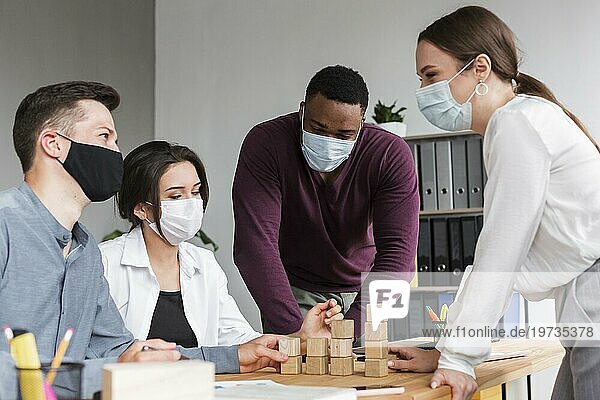 Menschen  die sich während der Pandemie mit Masken im Büro treffen