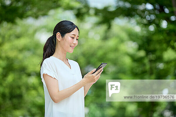 Japanese woman using smartphone in a city park