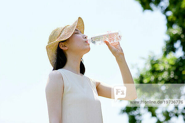 Young Japanese woman drinking water outside