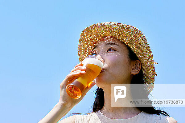 Young Japanese woman enjoying a cold beer outside