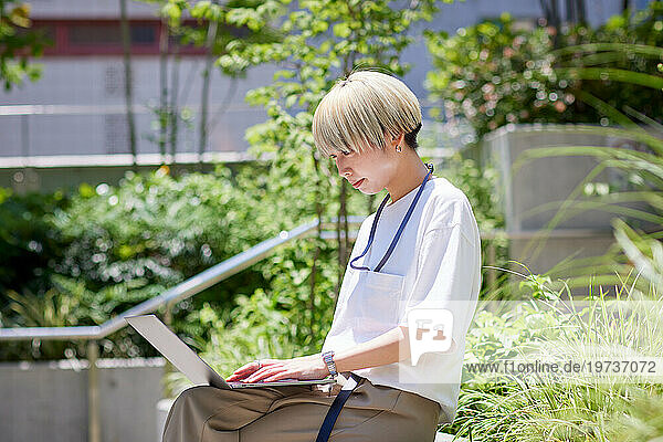 Young Japanese woman working on her laptop downtown Tokyo
