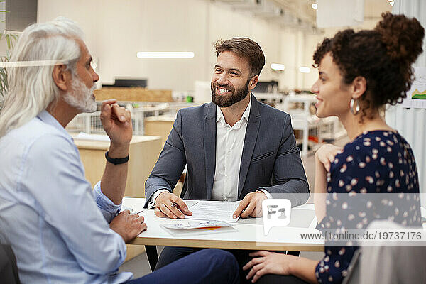 Adult couple discussing about contract with financial advisor
