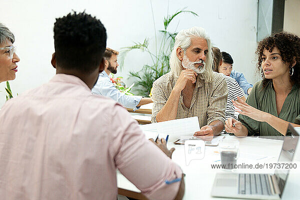 Businesswomen and businessmen discussing while gathered at office
