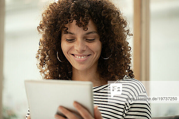 Young adult woman smiling while using digital tablet