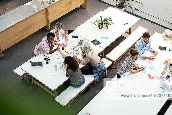 Wide view of place of work full of people having casual meetings