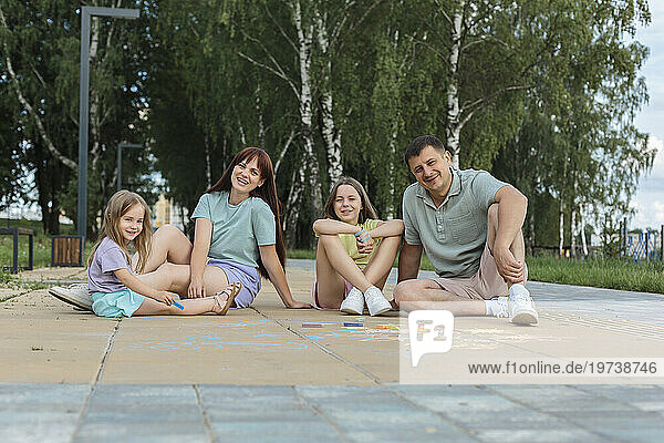 Smiling family sitting and enjoying on footpath at park