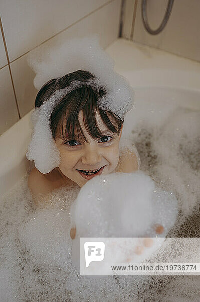 Boy playing with soap sud in bathtub at home