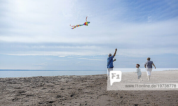 Grandparents flying kite with grandson at beach