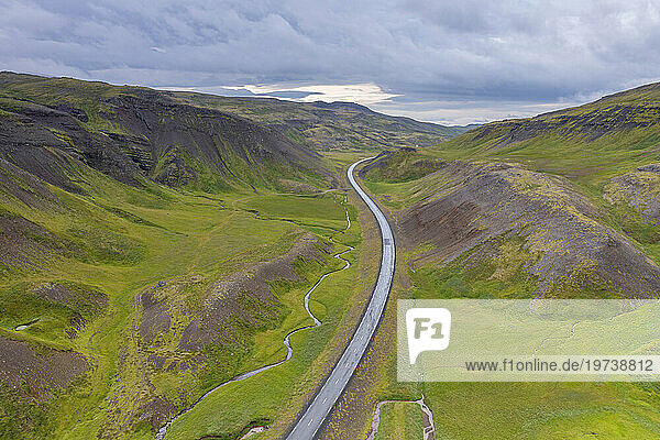Iceland  Aerial view of remote road and stream stretching between hills