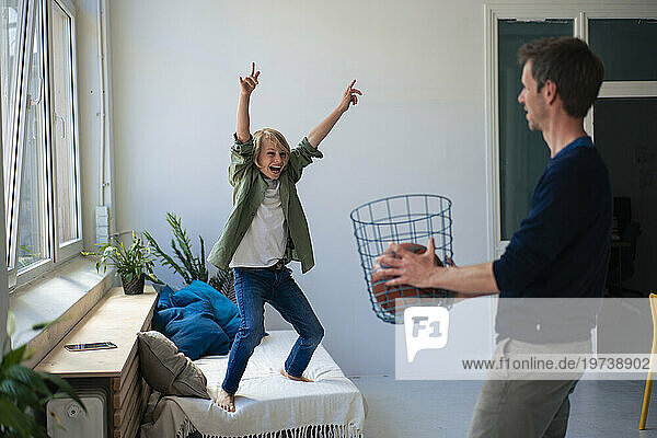 Cheerful boy winning and playing basketball with father at home