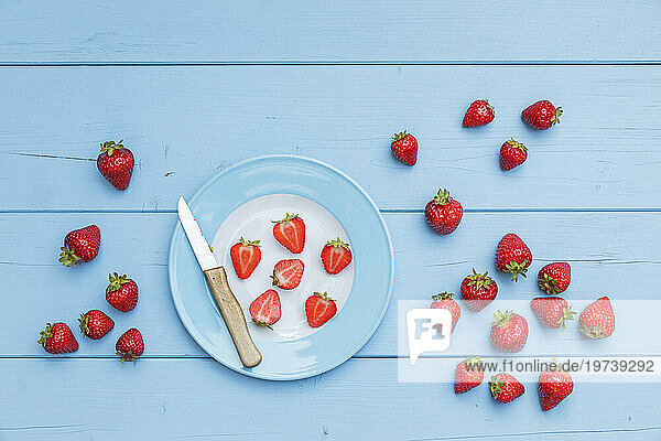 Plate  kitchen knife and ripe strawberries on blue wooden surface