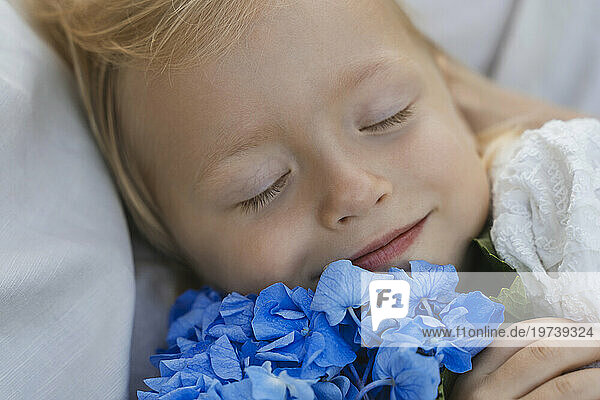Smiling girl relaxing with blue flowers