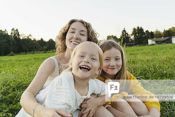 Happy mother and daughters enjoying together on grass