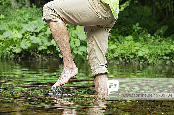 Senior man walking barefoot in river