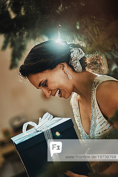 Smiling woman holding Christmas present at home