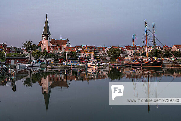 Denmark  Bornholm  Ronne  St Nicholas Church and surrounding houses reflecting in coastal water at dusk