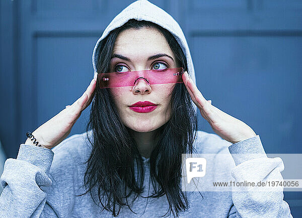 Young woman wearing pink lipstick and adjusting smart glasses