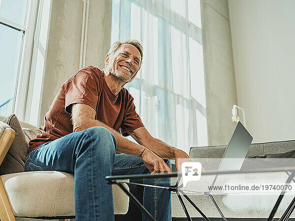 Happy man with laptop on table at home