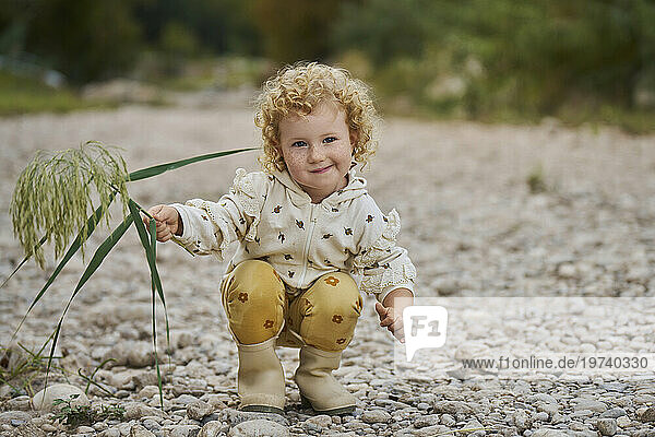 Smiling cute girl crouching with twig