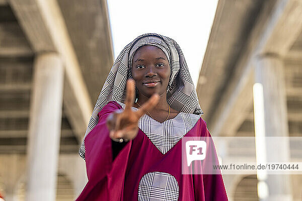 Young woman with hijab gesturing peace sign