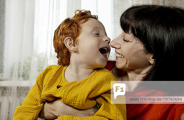 Happy mother having fun with son in front of window at home