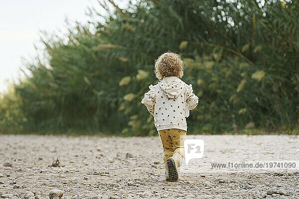 Blond girl running in front of plants