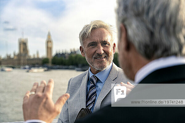 Happy businessman discussing with colleague in front of river