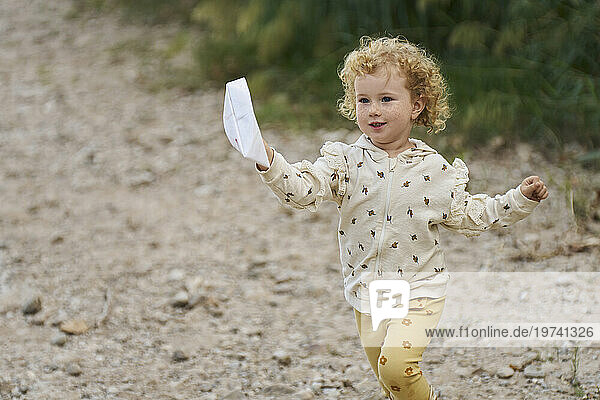 Smiling girl running with paper boat