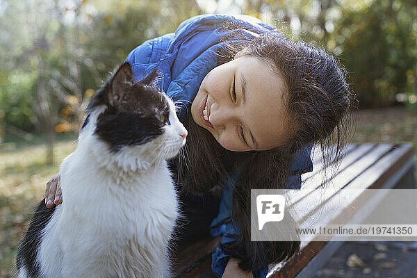 Happy girl playing with cat at park
