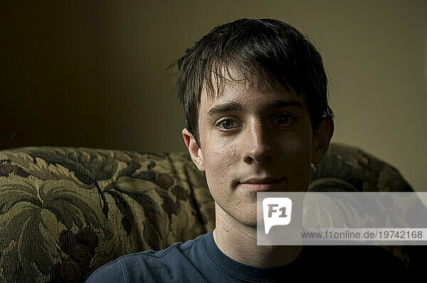 Teenage boy relaxes in an armchair; Lincoln  Nebraska  United States of America