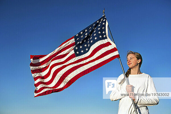 Teenage girl proudly holds an American flag; Lincoln  Nebraska  United States of America