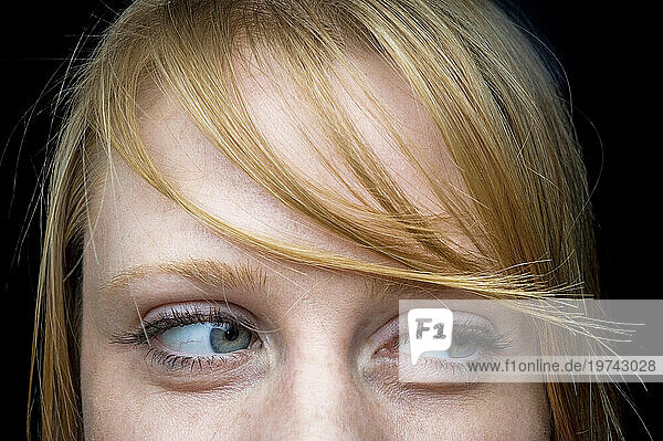 Close up of a young woman's eyes with wispy blond bangs looking to the side; Studio