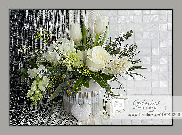 Flower art with a white floral bouquet and caption 'Grieving with you'; Studio